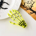 Détail macro d'une pince à cheveux main de squelette vert fluo pour Halloween - Jaune Citron
