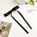 Detailed macro view of black satin bow hair clip with elegant long ribbons on a white tray - Black