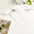 Detail of elegant white long ribbon bow hair clip in silky satin on decorative tray - White