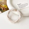 Detailed macro view of soft cream plush hair scrunchie with a resin joint on white plate - Ribbed Beige