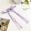 Close-up of lavender ribbon bow hair clip with long tassels on a white tray - Purple