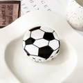 Detailansicht einer glänzenden Haarklammer im Fußball-Design auf einem Keramikteller - 7cm / Schwarz-Weißer Fußball