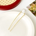 Dettaglio di forcina a U dorata con grande perla bianca su un vassoio di ceramica - Perla Singola Diritta / Oro