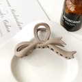 Detail view of a matte brown bow hair claw clip styled on an elegant ceramic plate - Hair Claw / Matte Light Coffee