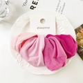 Detalle de cuatro coleteros de tela rosa suave dispuestos en un plato blanco decorativo - Serie Rosa