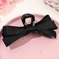 Dettaglio ravvicinato della grande molletta per capelli in raso nero su piatto rosa - Base Nera Nero