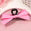 Gros plan d'une pince à cheveux à nœud en ruban rose sur un plateau décoratif rose - Noir et Rose