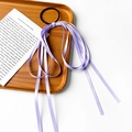 Dettaglio dell'elastico per capelli con lunghi nastri lavanda su vassoio di legno - Viola