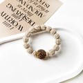 Detailed close-up of beige woven beads with a sparkling brown rhinestone center on the band - Twisted Ball Style / Beige