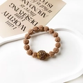 Close-up of brown woven hair tie with a gold pavé crystal bead on minimalist background - Twisted Ball Style / Light Coffee