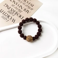 Detail view of brown knit beads and a gold sparkling rhinestone bead on a white tray - Twisted Ball Style / Dark Coffee