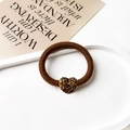 Detailed macro view of a brown knit scrunchie featuring a luxury rhinestone heart charm - Heart Pendant / Brown