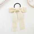 Dettaglio del fiocco in velluto crema con lunghi nastri su un elegante tavolo bianco - Stile Bianco Crema (Elastico)
