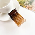 Detalle de una pinza para el pelo de carey ámbar junto a una taza de café blanca - 3cm Cuadrícula Tres Dientes - Café Gelatina