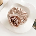 Close-up of champagne satin scrunchie with large fabric rose on white ceramic plate - Satin Rose Large Scrunchie / Khaki