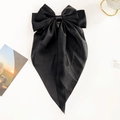 Detail view of a vintage black satin bow hair clip with long ribbons on a decorative desk - Black