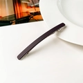 Dettaglio della lunga molletta per capelli viola opaco su un piatto in ceramica bianca - Marrone Scuro