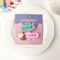 Détail de la pince à cheveux rose avec cornet de glace et nœud bleu sur une assiette - Nœud Bleu Paon