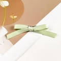 Detail view of a soft green satin ribbon bow hair clip with a silver metal duckbill base - Single Style / Grass Green
