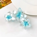 Dettaglio di tre fiori di frangipane in resina blu sfumato su una grande pinza per capelli - Blu Perlato