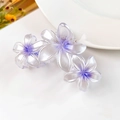 Dettaglio di una grande pinza per capelli viola traslucida con tre fiori di frangipane - Viola Perlato