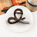 Macro shot of minimalist translucent coffee brown acrylic hair claw clip on a white plate - Transparent Dark Coffee