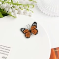 Détail de la pince à cheveux papillon orange en acrylique avec motifs ailes réalistes - Orange