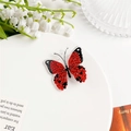 Détail d'une pince à cheveux papillon en acrylique rouge sur un plateau décoratif - Rouge