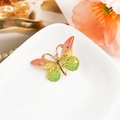 Détail de la pince papillon en émail dégradé avec texture d'écailles sur plateau - Résine Mixte / Dégradé Orange-Vert