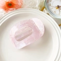 Close-up of a pale pink acetate hair claw clip with marble texture on a white decorative plate - Iridescent Pink (10.5cm Round Clip - PVC Iridescent Pink)