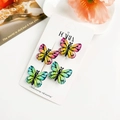 Détail de quatre pinces à cheveux papillon dégradées avec des ailes texturées sur carte - Résine Mixte / Vert + Jaune