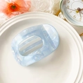 Detail view of light blue marble textured acetate hair claw clip on a ceramic tray - Iridescent Blue (10.5cm Round Clip - PVC Iridescent Blue)