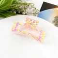 Detail shot of a transparent hair claw clip with floral patterns on a white plate - Colorful Sunflower (8.5cm Square)