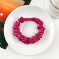 Primer plano de un coletero de satén rojo rosa con hebilla en plato blanco decorativo - rosa intenso