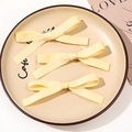 Three-piece set of pale yellow satin ribbon bow hair clips on a ceramic plate - Combination Style / Milky Yellow
