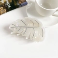 Détail macro d'une pince à cheveux feuille de Monstera au fini nacré et textures - Blanc Sirène