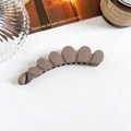 Détail de la pince banane évidée marron café mat aux bords ondulés sur un décor de table blanc - Pince Banane Os de Dragon 11cm - Café au Lait Mat