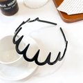 Detail shot of wavy black toothed headband resting on a coffee cup in a cozy setting - Medium Wave Headband / Glossy Black