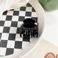 Vista de detalle de la mini pinza para el pelo negra brillante en una bandeja de cuadros - Negro