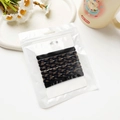 Détail de cinq élastiques à cheveux tressés noirs et marron dans une pochette transparente - 97 cm / Café Foncé