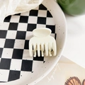 Detalle de una pinza para el cabello mate blanco crema en un plato de cuadros - Blanco Leche