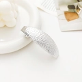 Detail shot of a silver long curved hair clip featuring an elegant hammered metal texture - Hammered Crater Oval Silver