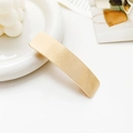 Detail showing the gold metallic spring hair clip with a brushed texture finish - Striped Rectangle Gold