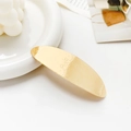 Detailed view of large golden metal hair clip with floral engraving on a ceramic tray - Floral Pattern Oval Gold