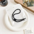 Close-up of black braided elastic hair tie with matte buckle in minimal packaging - Plastic/Resin / Threaded Adjustable Hair Tie - Black Buckle Black