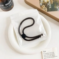 Brown threaded adjustable hair tie in frosted packaging placed on a ceramic plate - Plastic/Resin / Threaded Adjustable Hair Tie - Black Buckle Dark Coffee