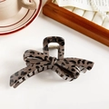 Detail of leopard print bow hair claw clip with metallic spring on a wooden tray - Dark Leopard Bow