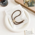 Close-up of brown textured hair tie with gold button in frosted zipper bag - Plastic/Resin / Threaded Adjustable Hair Tie - Bronze Buckle Dark Brown