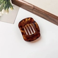 Macro detail of amber tortoiseshell hair claw clip with golden spring on elegant background - Glossy Coffee Leopard