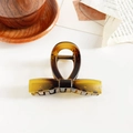 Detail view of amber textured claw clip with bow design on a minimalist background - 8cm Solid Bowknot / Matte Tortoiseshell